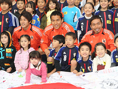 現地の子供たちと記念撮影する内田（左）ら日本代表イレブン
