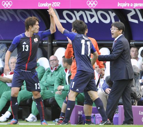 後半、決勝ゴールを決め、鈴木（左）とタッチする永井。右は関塚監督