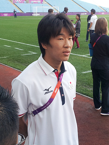 試合会場のピッチ横で報道陣の質問に答える永井