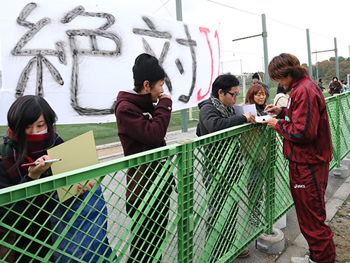 サポーターの掲げる「絶対Ｊ１」の垂れ幕を前に、ファンにサインする神戸・大久保