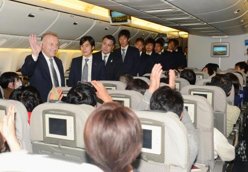 帰国便の機内で、サポーターにあいさつするザッケローニ監督（左端）らサッカー日本代表