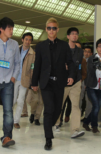 報道陣を引き連れ、黒いスーツで空港を歩く本田圭佑