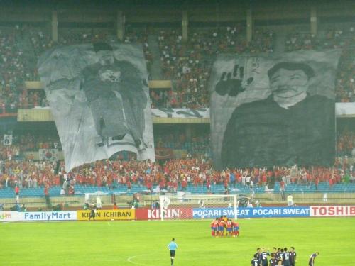 サッカー東アジア杯男子の日韓戦で、試合開始直前に韓国応援団が広げた安重根（右）らの肖像を描いた巨大な幕