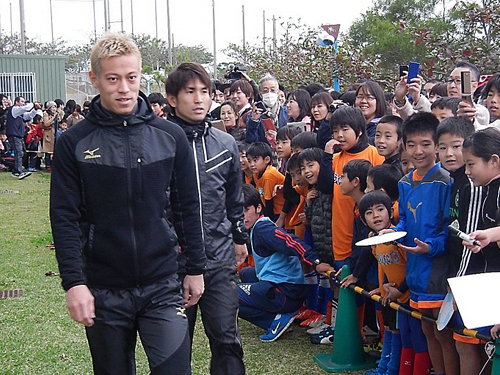 大勢の子どもたちに迎えられて登場する日本代表ＭＦ本田（左）