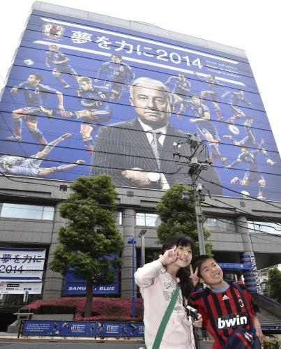 ＪＦＡハウス壁面を飾るサッカー日本代表のザッケローニ監督と選手の姿を前に、記念写真を撮る子どもたち＝15日午後、東京都文京区