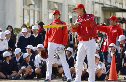 広島市立梅林小を訪れ、バッティングを披露するプロ野球広島の堂林選手（手前右）。左は中田投手＝27日午前