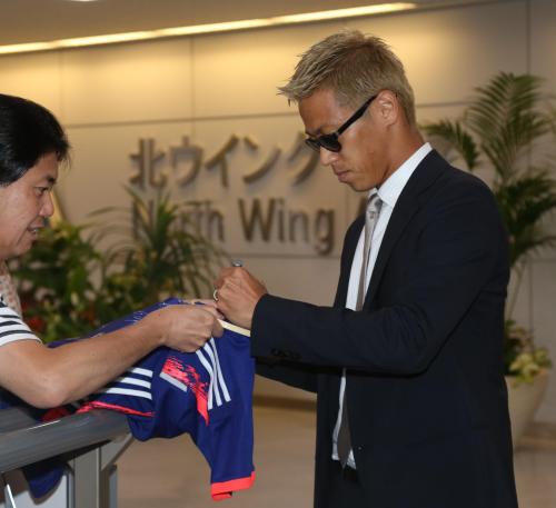 成田空港に到着した本田はファンへのサインに応じる