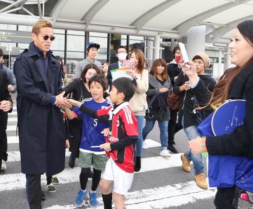 帰国した本田は笑顔で子どたちと握手する