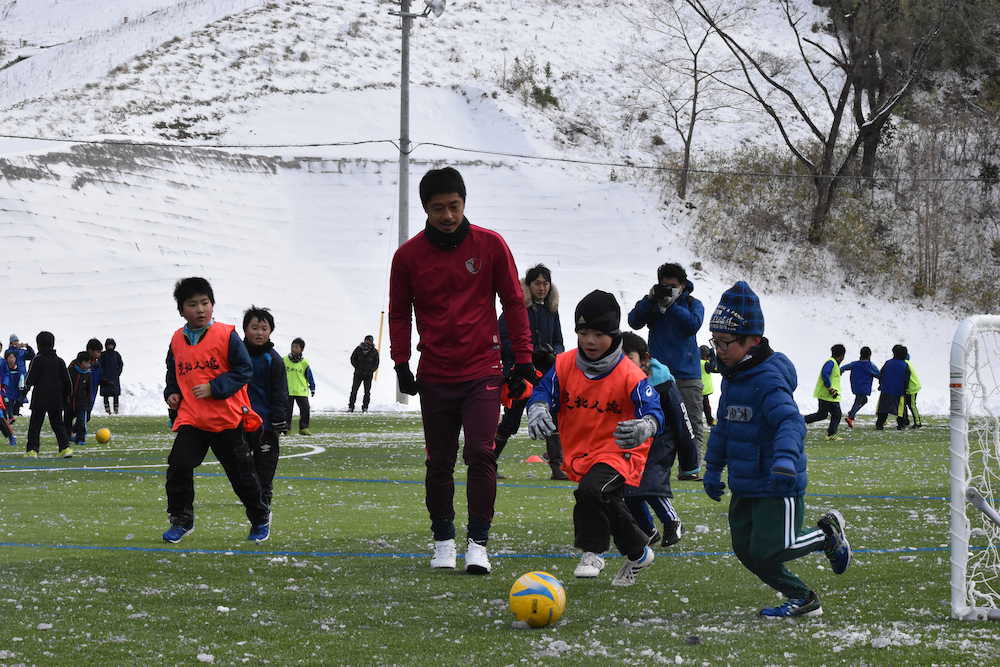 昨年１２月、人工芝化した岩手県大船渡市の赤崎グラウンドで子どもたちとサッカーをする小笠原