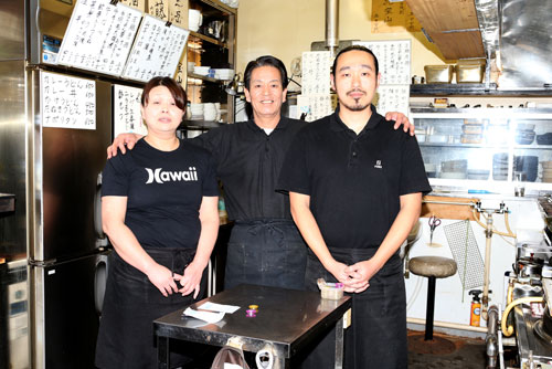 厨房でポーズをとる（左から）店員の大内邦枝さん、代表の村山智也さん、調理師の村田賢一さん