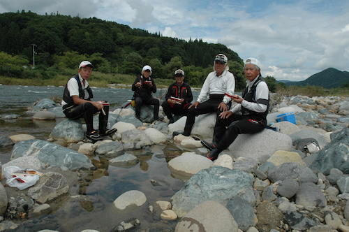 釣る手を休めて河原で仲間たちと昼食。釣り談義に花が咲く（左から２人目が筆者）