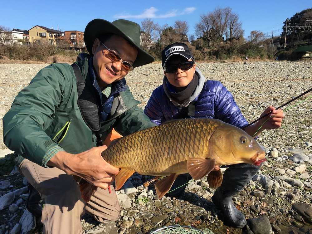 このサイズのコイがフライで釣れる。年明けに浅川で遊んだ筆者（左）と次男の尚樹さん