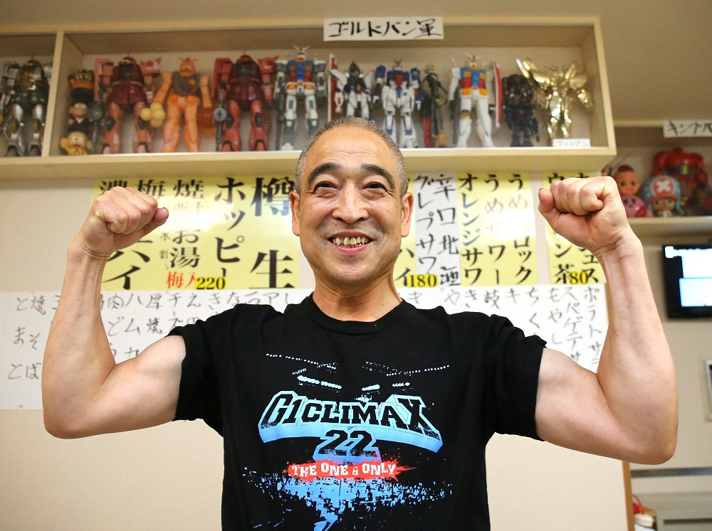 「良心的な店　あさひ」店主の斉藤松栄さんは自身の作製したフィギュアの前でポーズ