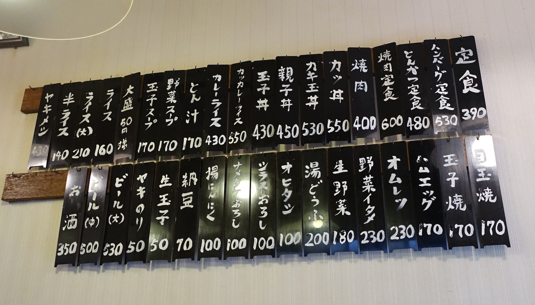 年季が入った壁のメニュー札。一番安い定食３９０円は生アゲ煮、ナスイタメなど種類も豊富