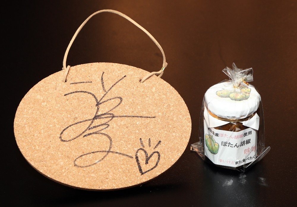 祥子のサイン入りボード（左）とぼたん胡椒の味噌加工品瓶詰めをプレゼント