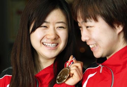 卓球の世界選手権から帰国し、混合ダブルスで獲得した銅メダルを手に笑顔の福原愛。右は石川佳純