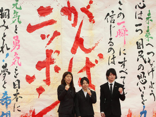 書道ガールズの応援メッセージの前で記念撮影する吉田沙保里、三宅宏美、内村航平