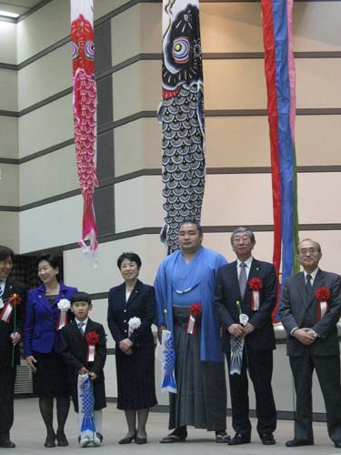 小宮山厚労相（左から２人目）ら掲げた鯉のぼりの前で記念撮影する鶴竜（左から５人目）