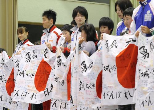 小学生から渡された寄せ書き入りの日の丸を手にする、ロンドン五輪体操代表の田中理恵選手（左端）や内村航平選手（中央）ら
