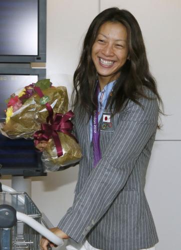 帰国し、花束を手に笑顔を見せる競泳の寺川綾