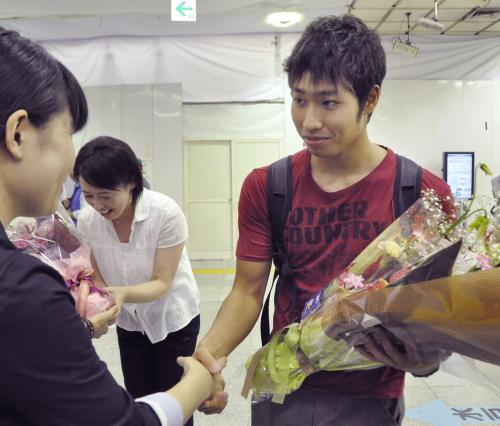 地元に戻り、花束を受け取る萩野公介選手。左奥は母貴子さん