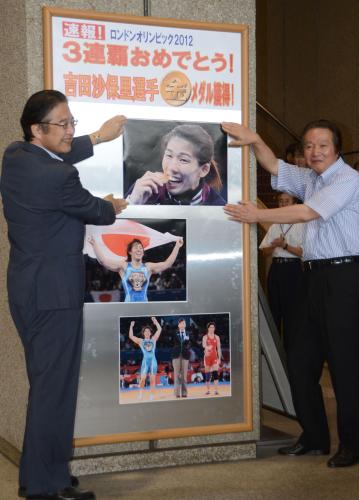 津市役所のロビーに、レスリング女子吉田沙保里の優勝を伝える写真を掲示する前葉泰幸市長（左）