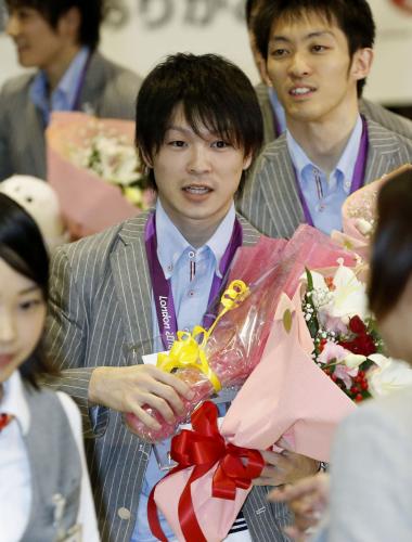 花束を手に、笑顔で帰国した体操の内村航平選手。右は田中和仁選手