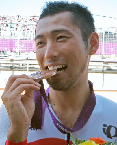 男子ロードタイムトライアルで獲得した銅メダルをかじる藤田征樹
