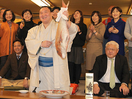 ＜大相撲九州場所１４日目＞優勝した白鵬は大きな鯛を持ち上げ笑顔を見せる（前列右は宮城野親方）