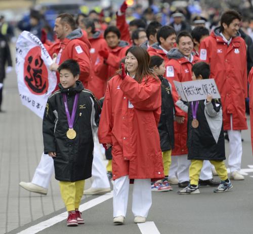 被災地の小学校から招待された児童とパレードに参加し、沿道に集まった市民に手を振る、レスリング女子金メダルの吉田沙保里選手（中央）