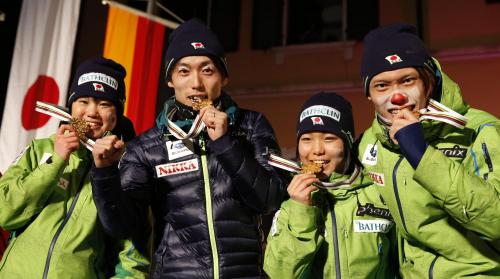 ノルディックスキー世界選手権のジャンプ混合団体で優勝し、表彰式でメダルをかむ（左から）伊藤有希、伊東大貴、高梨沙羅、竹内択