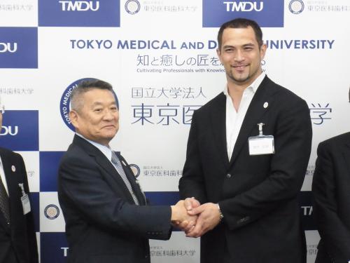 東京医科歯科大の吉澤靖之学長（左）と握手する室伏