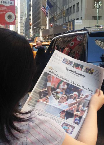 錦織圭の決勝進出を大きく報じるニューヨークの地元紙を読む人