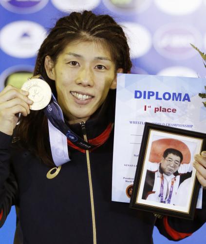 金メダルと父栄勝さんの写真を手にする吉田
