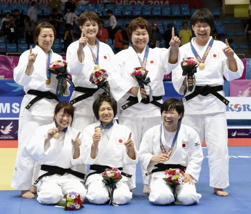 柔道女子団体で優勝し、金メダルを胸に笑顔でポーズをとる日本。前列左から山岸、中村、山本。後列左から阿部、新井、稲森、梅木