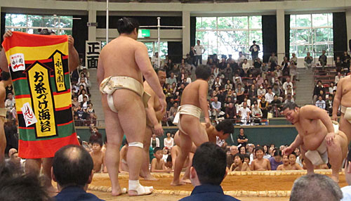 遠藤（右から２人目）が子供と稽古している最中、永谷園のバスタオルを広げて土俵上を周回する力士が登場