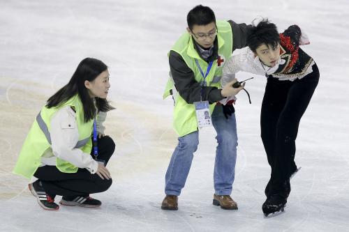 男子フリーの直前練習中に中国選手と激突し、抱えられながら立ち上がる羽生（ＡＰ）
