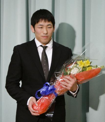 引退記者会見で花束を手にするレスリング男子の米満
