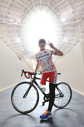 自転車の前でＶサインを見せる藤井美穂