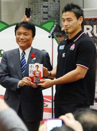 福岡県の小川知事（左）に自著を渡すラグビー日本代表ＦＢ五郎丸