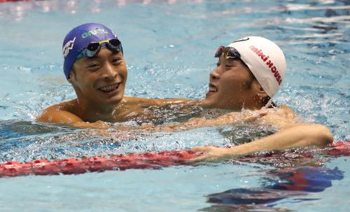 ともに１００ｍ背泳ぎでの五輪出場を決め、喜びを分かち合う入江（左）と長谷川