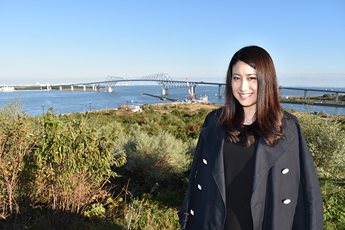 東京ゲートブリッジをバックに笑顔の田中琴乃さん
