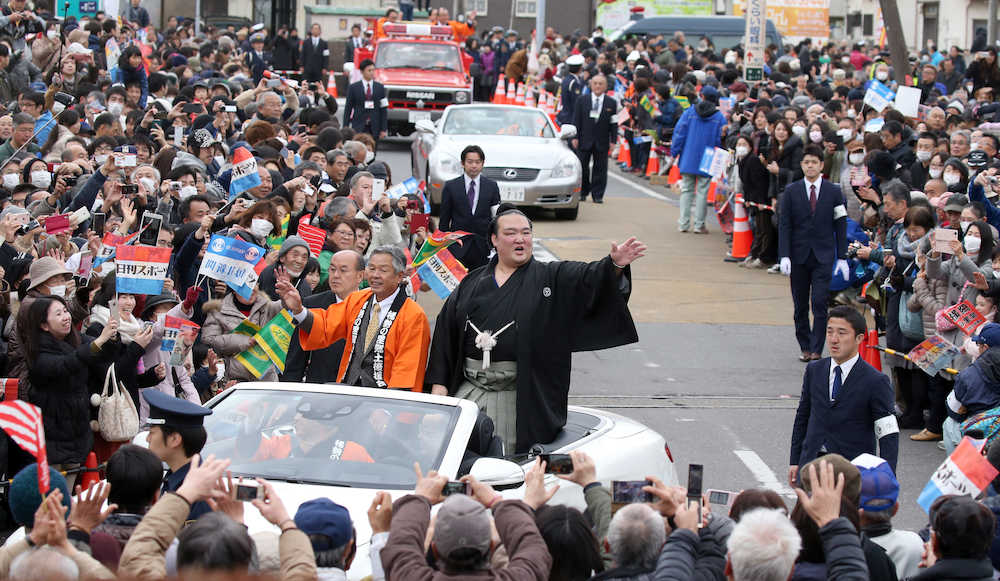 牛久祝賀パレードで沿道のファンの祝福に手を振り応える稀勢の里。左は根本洋治・牛久市長