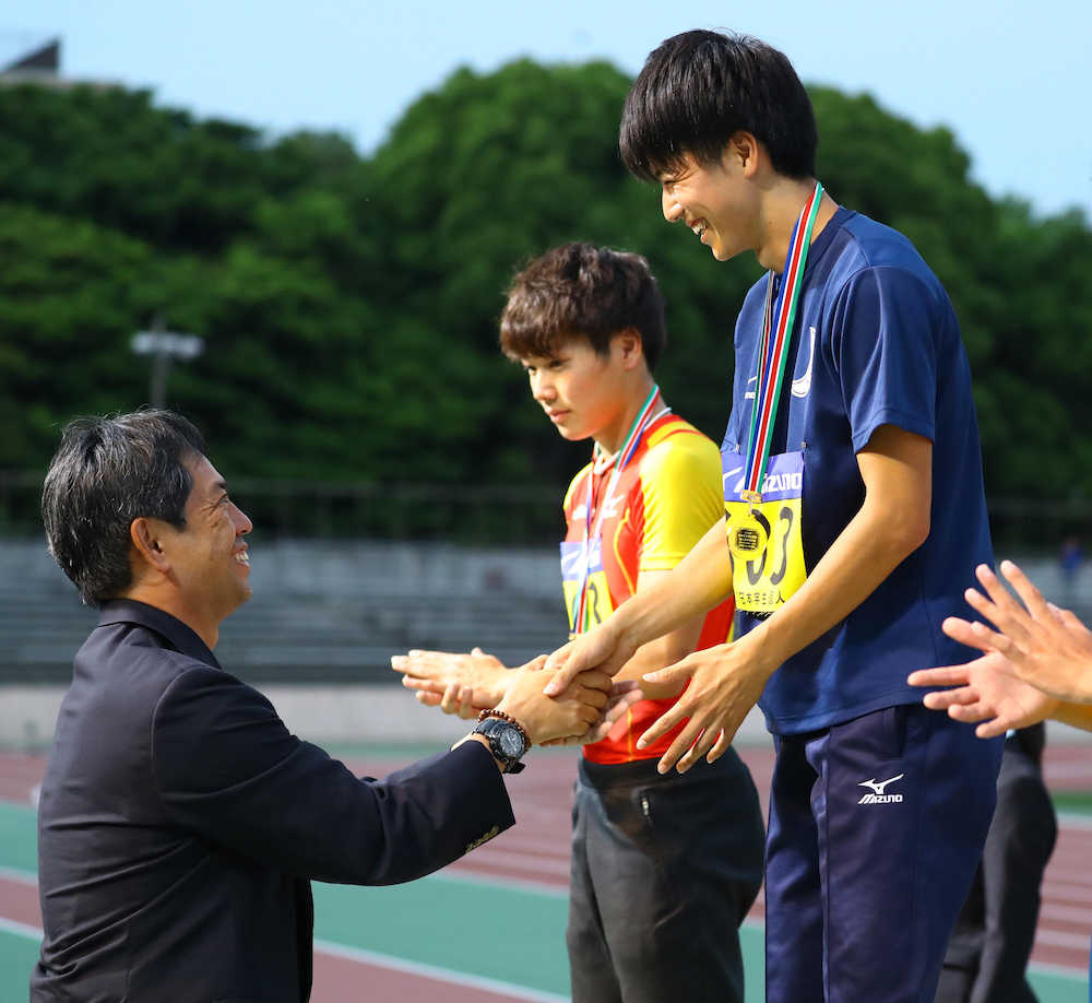 男子１００メートル決勝、１０．０８で優勝し日本陸連・伊東浩司強化委員長からメダルを贈られ笑顔で握手を交わす多田（右）