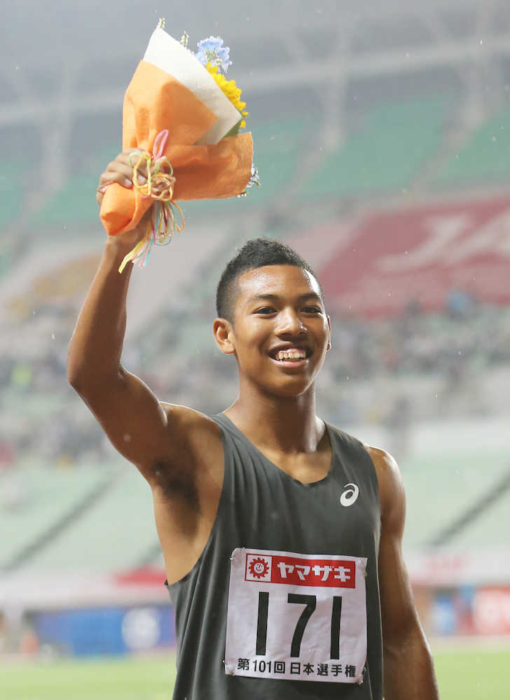 男子１００メートル決勝で優勝して花束を掲げるサニブラウン