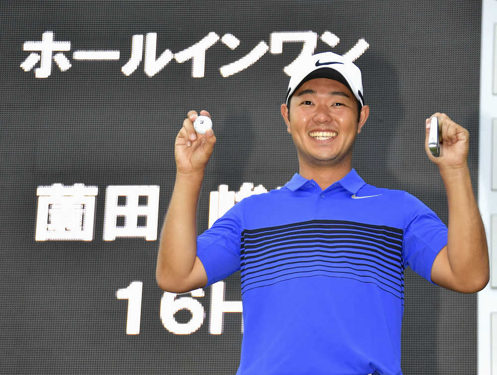 １６番でホールインワンを達成した薗田峻輔は、ボードの前で５番アイアンとボールを手に笑顔を見せる
