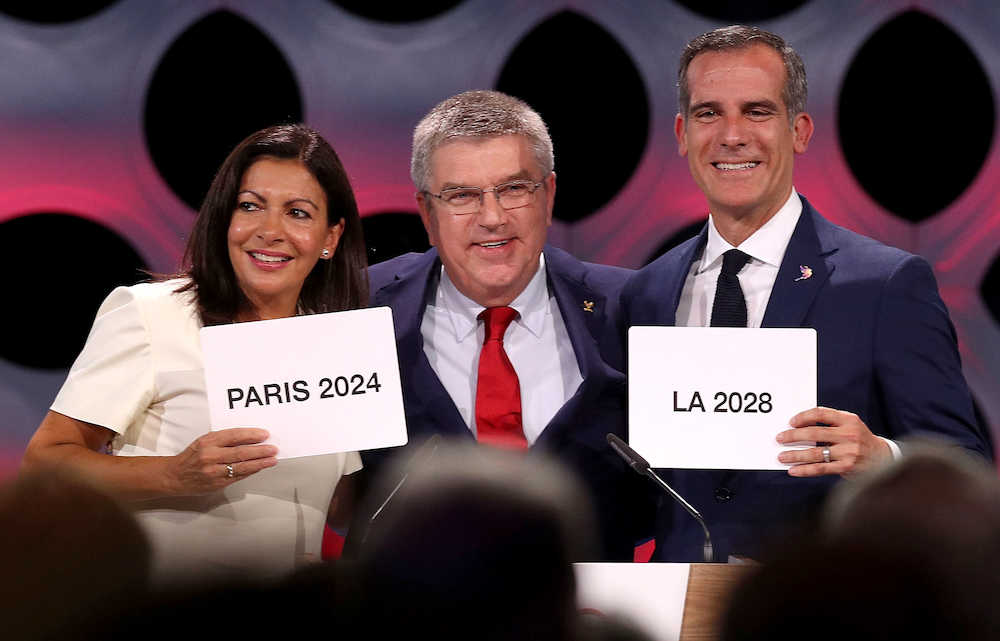 夏季五輪の開催都市に決まり、国際オリンピック委員会のバッハ会長と笑顔を見せる２４年パリのイダルゴ市長（左）と２８年ロサンゼルスのガーセッティ市長（右）＝１３日、リマ