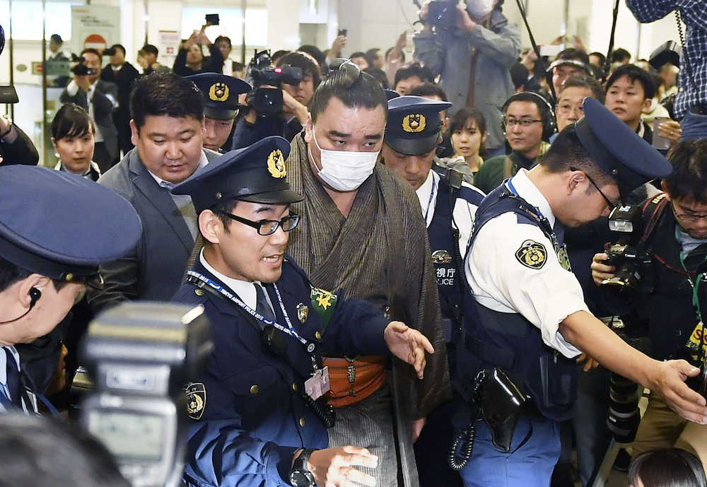 羽田空港に到着し、警察官に囲まれて車に向かう大相撲の横綱日馬富士＝１６日午後１１時４分