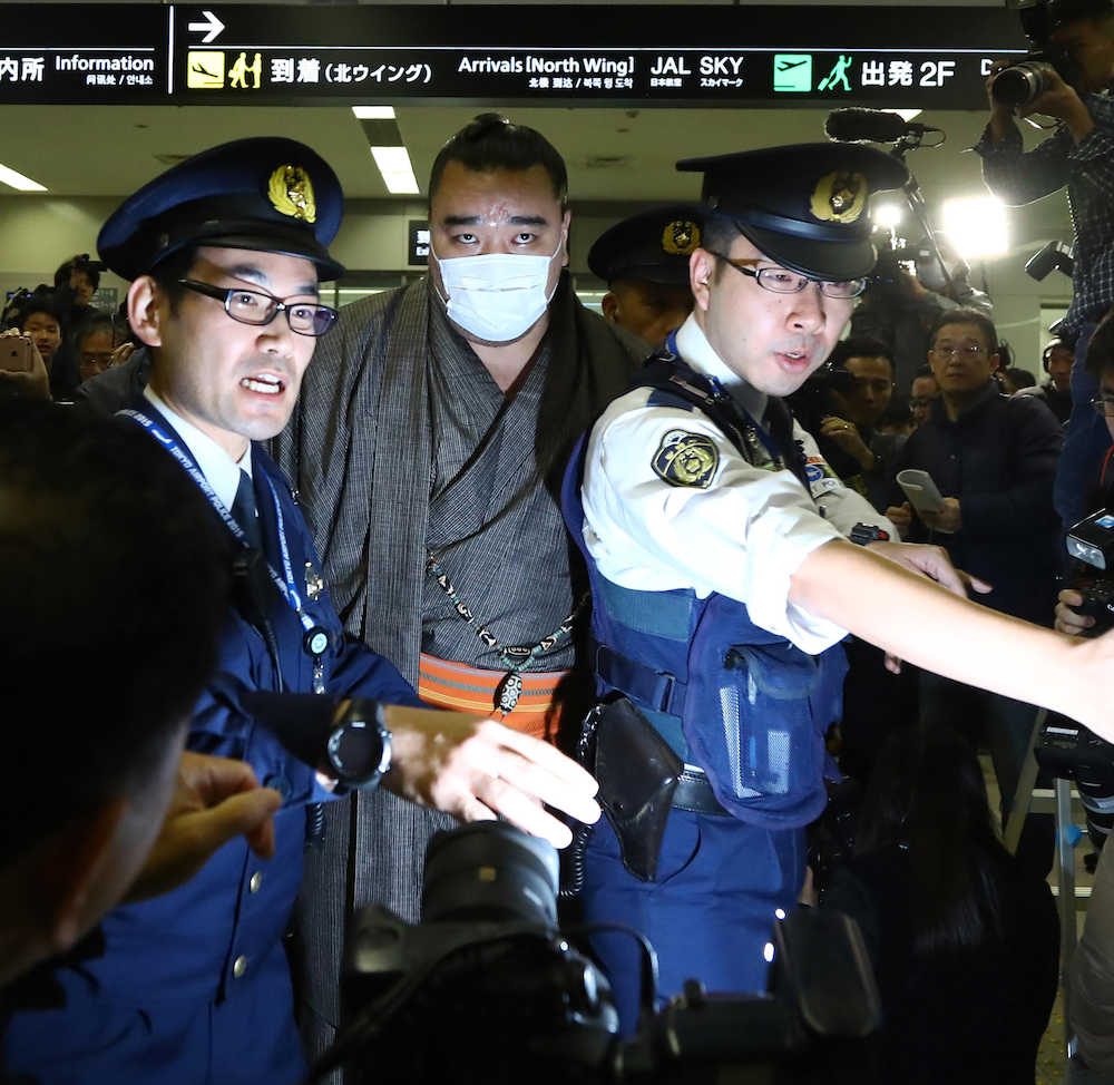 １６日午後１１時過ぎ、警察官に囲まれながら羽田空港で車に乗り込む日馬富士（中央）