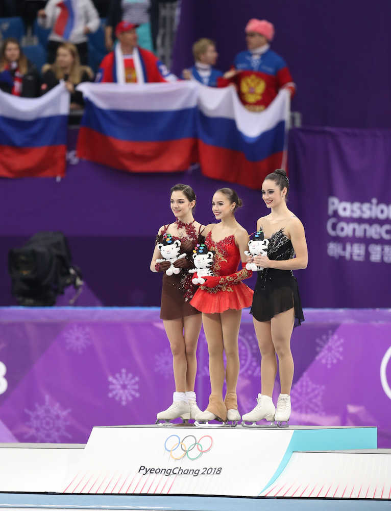 女子フリー、ロシア国旗が揺れる中で表彰台に上がる（右から）オズモンド、ザギトワ、メドベージェワ（撮影・小海途　良幹）